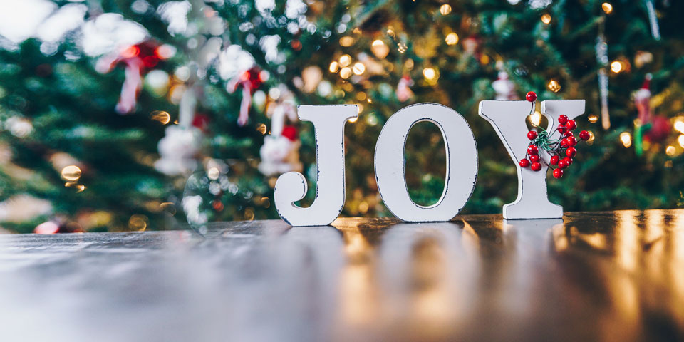Joy letters in front of a Christmas tree
