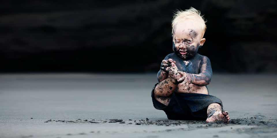 a child sitting on the ground covered in mud