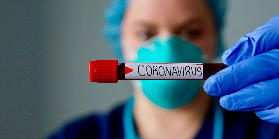 A medic looking at a test tube with “Coronavirus” written on it