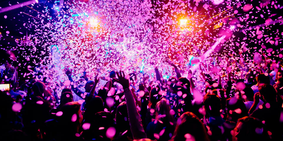 A blurred picture showing a crowd of people with their hands in the air
