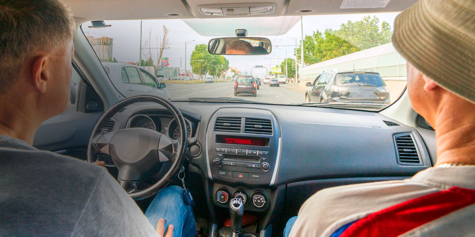 a picture taken from the back seat of a car showing two men sitting in the front