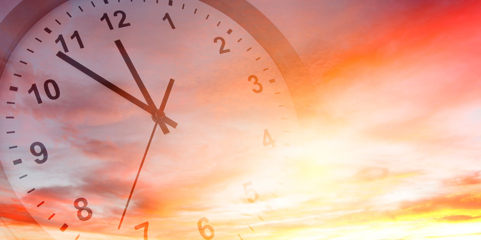a faded clock set against a picturesque sunset