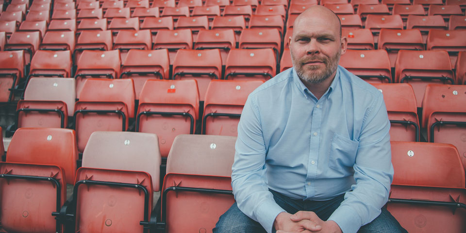 Simon Edwards sitting on a seat in an empty football stadium